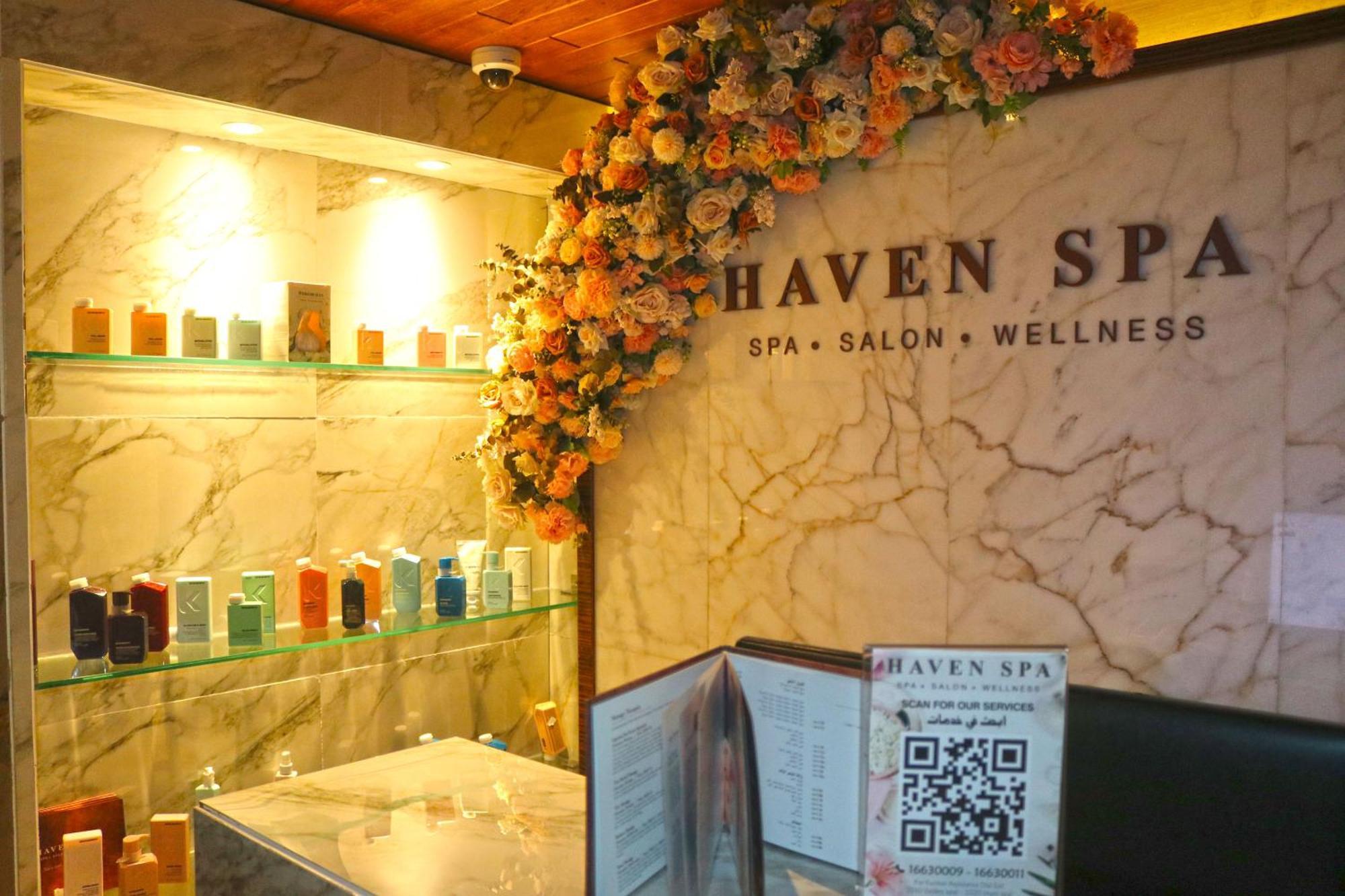 Lagoona Beach Luxury Resort And Spa Manama Exterior photo The photo shows the interior of a spa called "Haven Spa." The wall is decorated with beautiful artificial flowers, creating an inviting atmosphere. There are several shelves displaying various colorful bottles and products, likely for skincare or wel