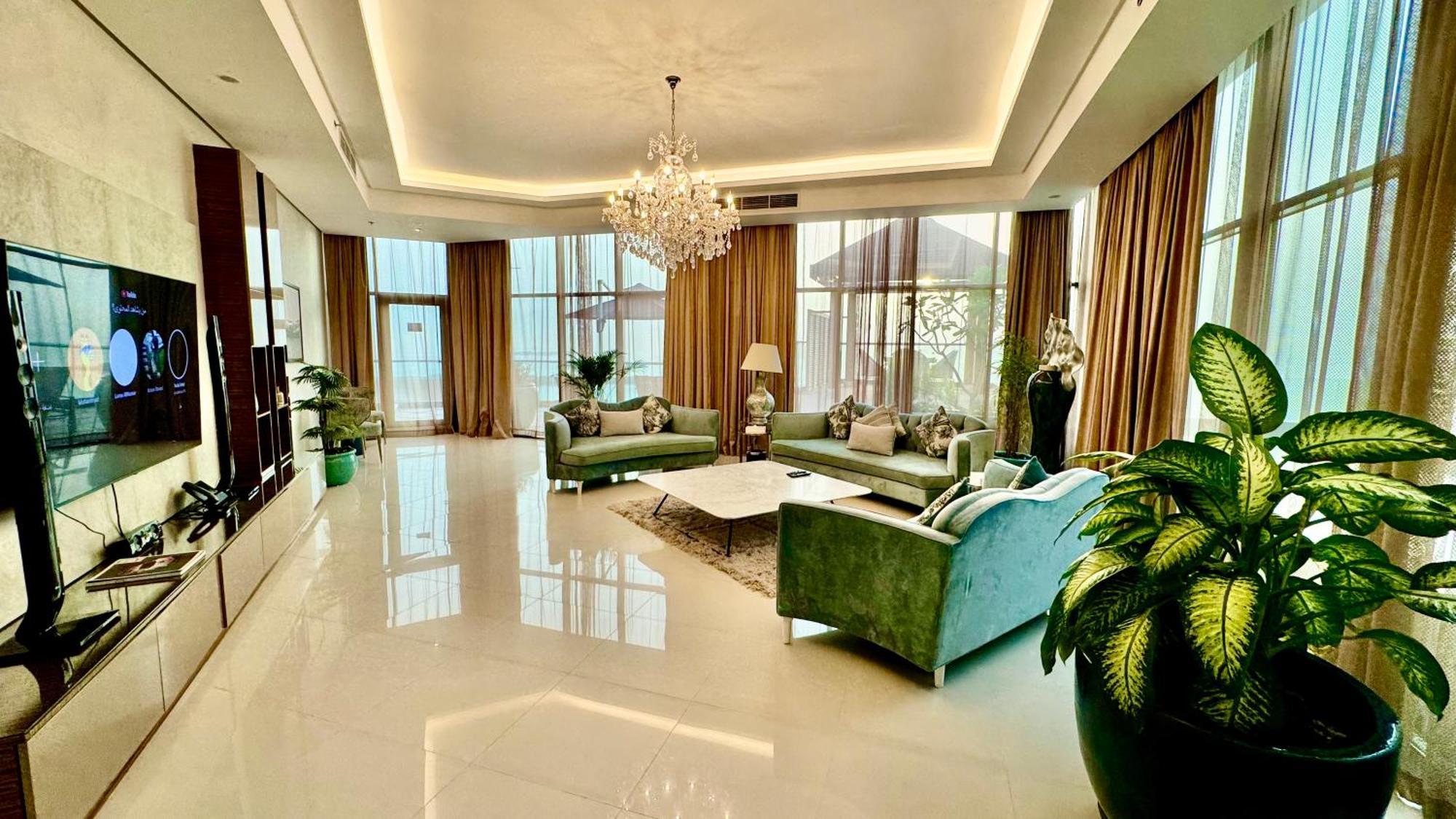 Lagoona Beach Luxury Resort And Spa Manama Exterior photo The photo depicts a spacious and elegantly designed living room. The room features large windows allowing natural light to flood in, accompanied by sumptuous curtains. The furniture includes a pair of soft green sofas and a centerpiece coffee table s