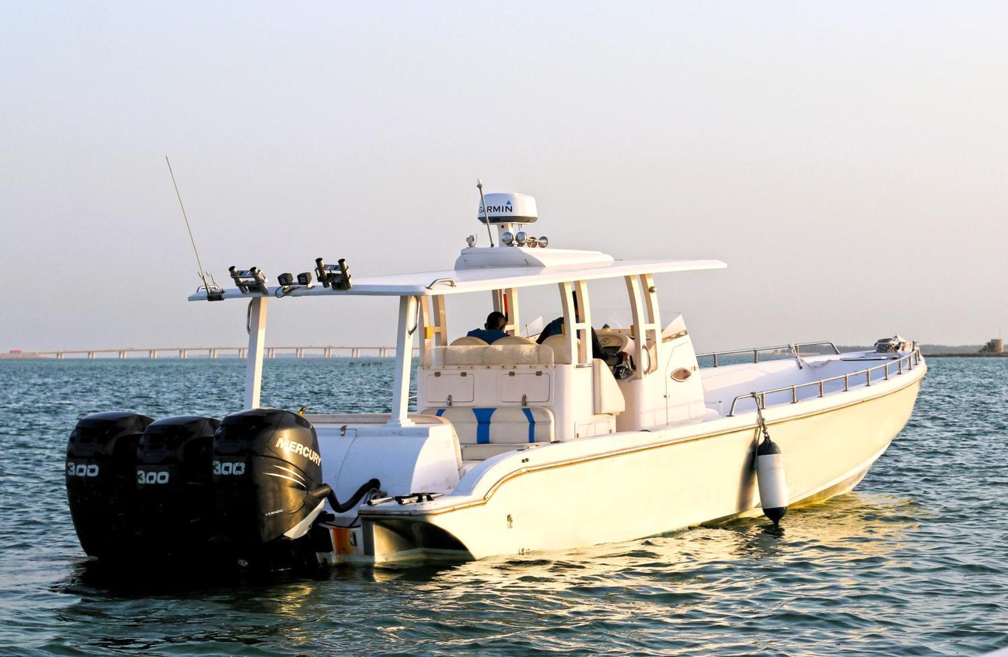 Lagoona Beach Luxury Resort And Spa Manama Exterior photo The photo shows a large, white motorboat equipped with three powerful outboard engines at the stern. The boat has a sleek design, with a spacious open deck and a covered cabin area that likely provides shelter and controls for navigation. The scene i