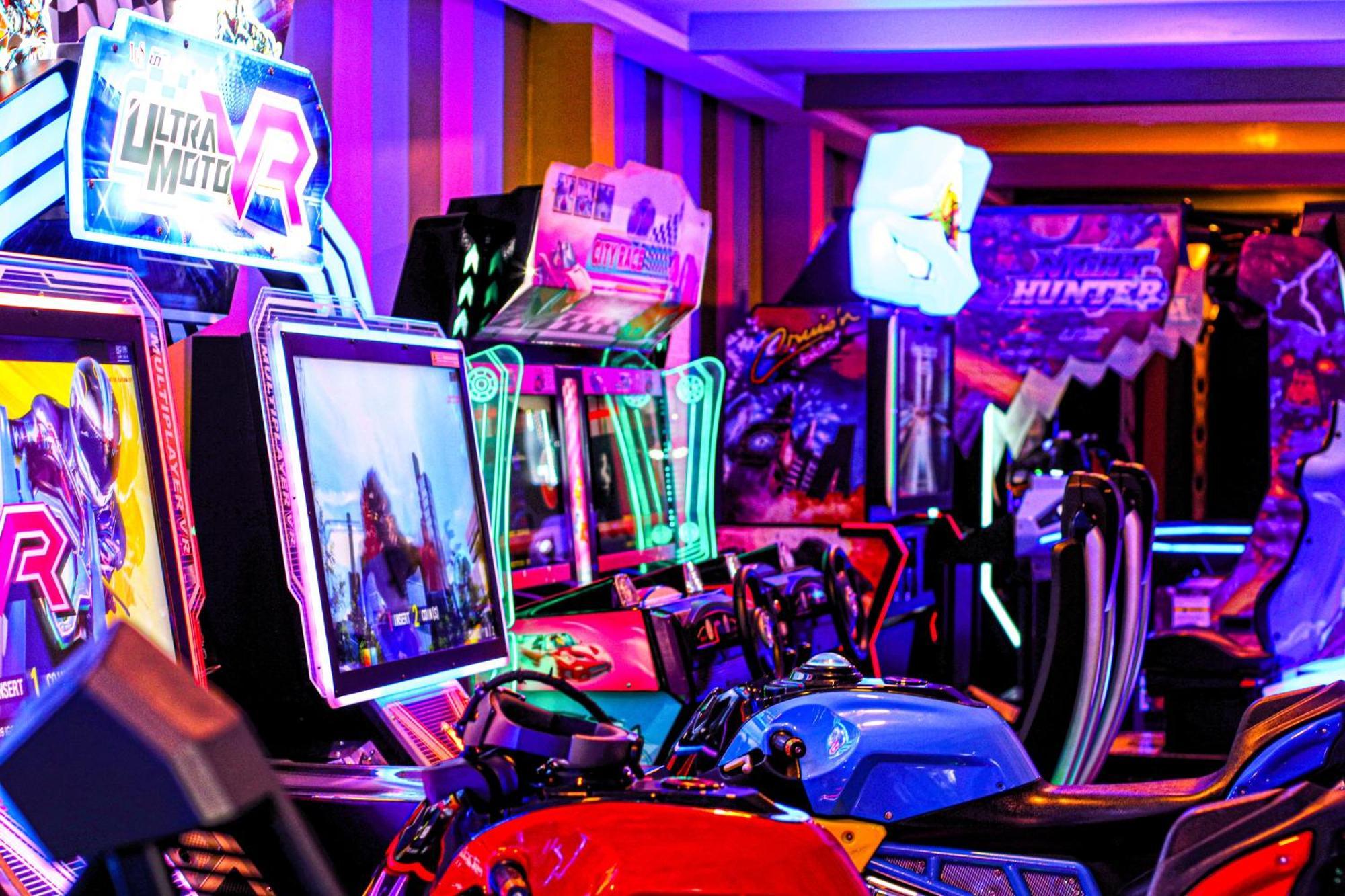 Lagoona Beach Luxury Resort And Spa Manama Exterior photo The photo shows a vibrant arcade scene featuring various arcade gaming machines. The machines are lined up, showcasing colorful screens and bright, neon lights, creating an energetic atmosphere. Some machines appear to be racing games, as indicated b