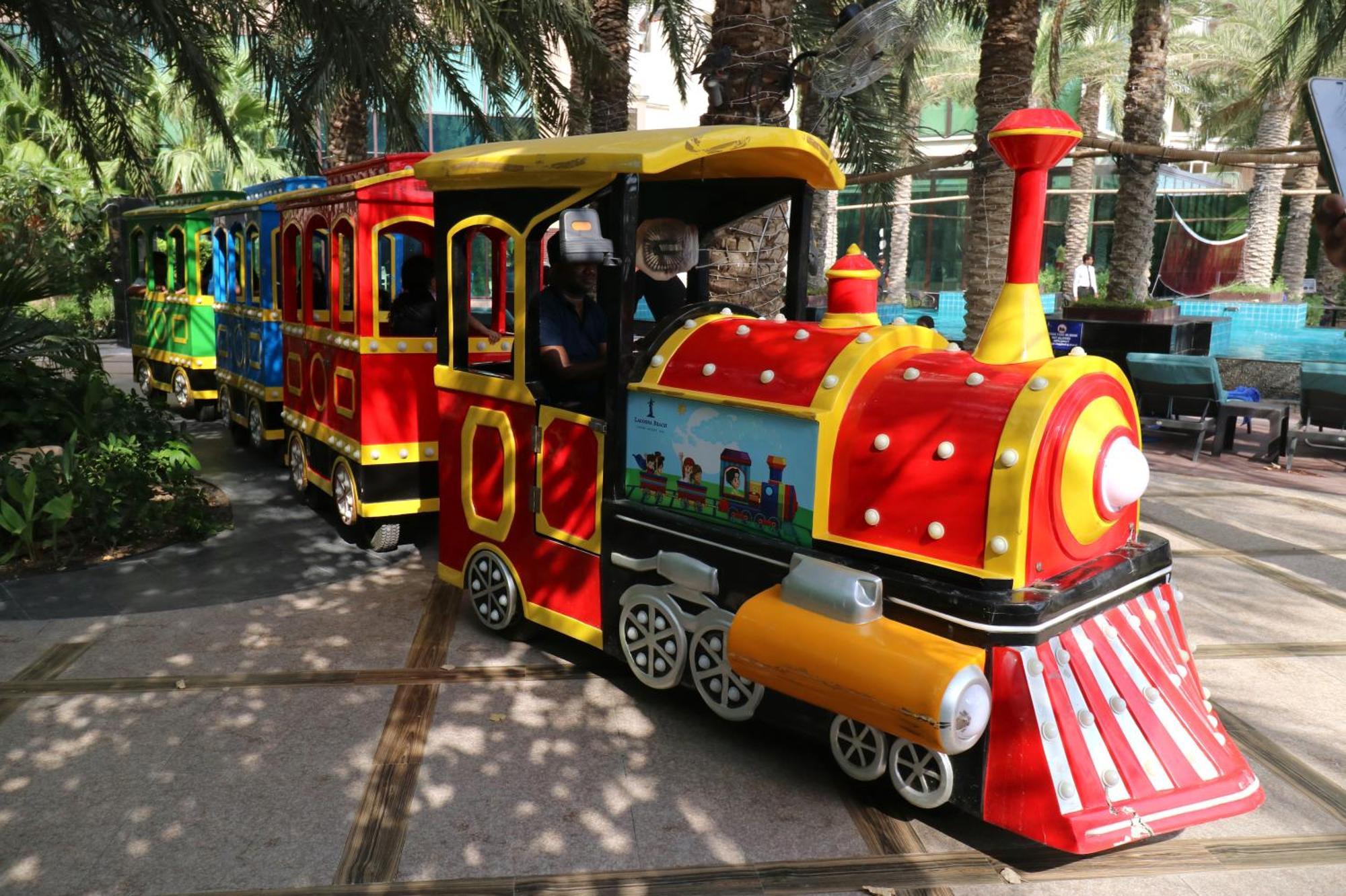 Lagoona Beach Luxury Resort And Spa Manama Exterior photo The photo shows a colorful miniature train. It features a vibrant design with bright red, yellow, and blue colors. The front of the train resembles a classic steam engine, complete with a prominent smokestack. The train is designed to resemble a fun 