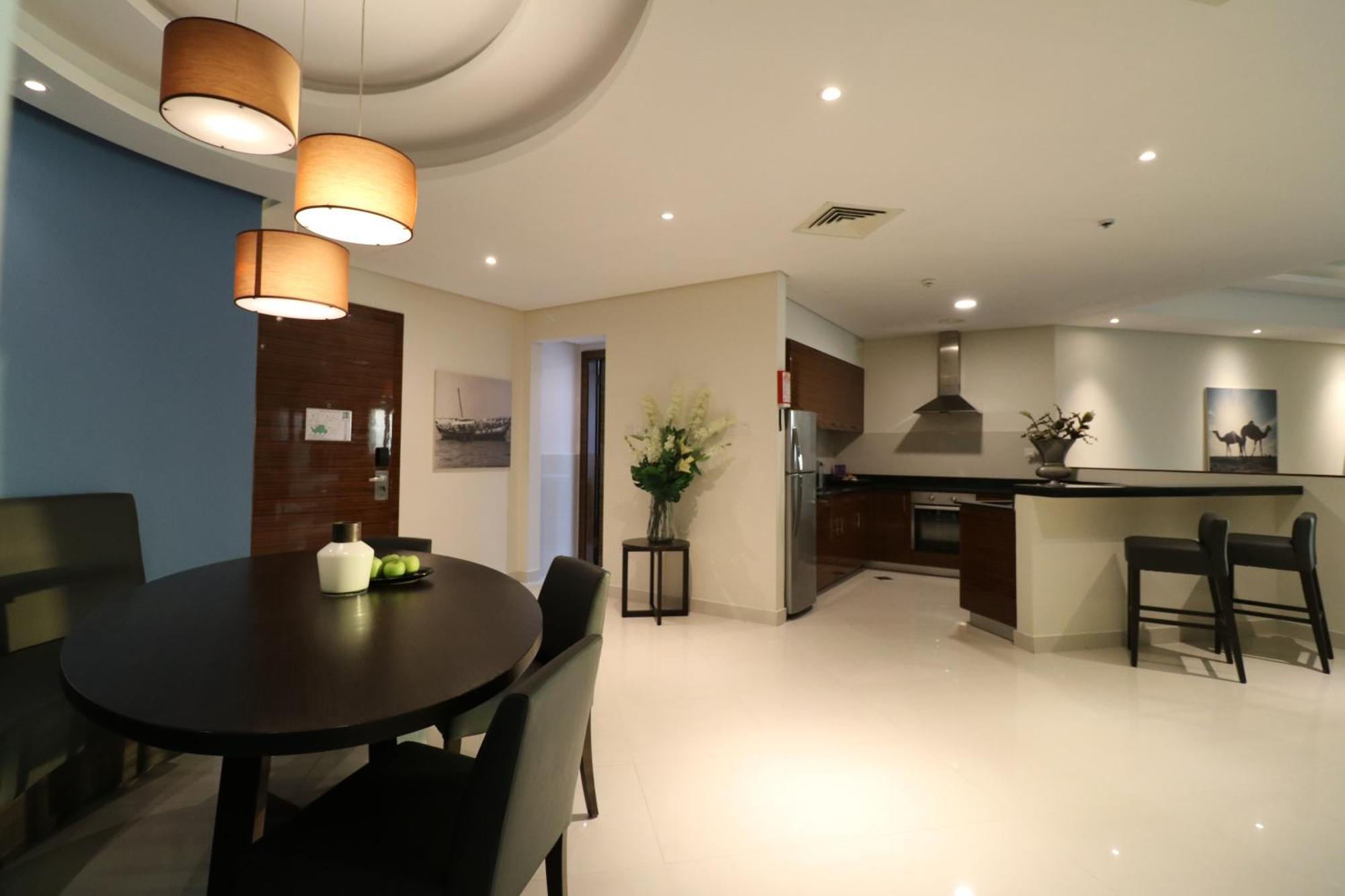 Lagoona Beach Luxury Resort And Spa Manama Exterior photo The photo shows a modern, open-concept dining and kitchen area. On the left, there is a round dining table with black chairs, accompanied by a few decorative elements like a small vase and some fruit. The walls have a combination of light and dark to