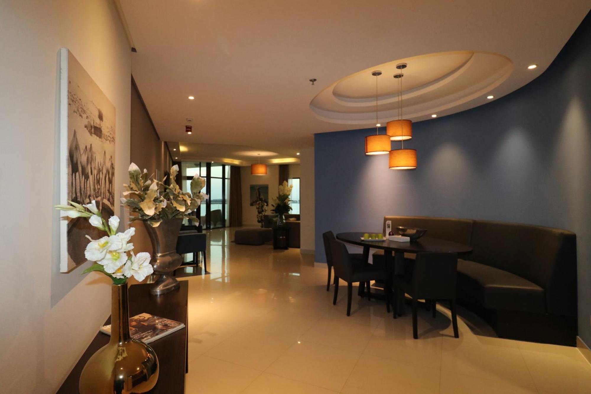 Lagoona Beach Luxury Resort And Spa Manama Exterior photo The photo showcases an interior space, likely a modern lounge or reception area. It features a combination of soft lighting, neutral-colored walls, and decorative elements. There are elegant light fixtures hanging from the ceiling, and a curved blue 