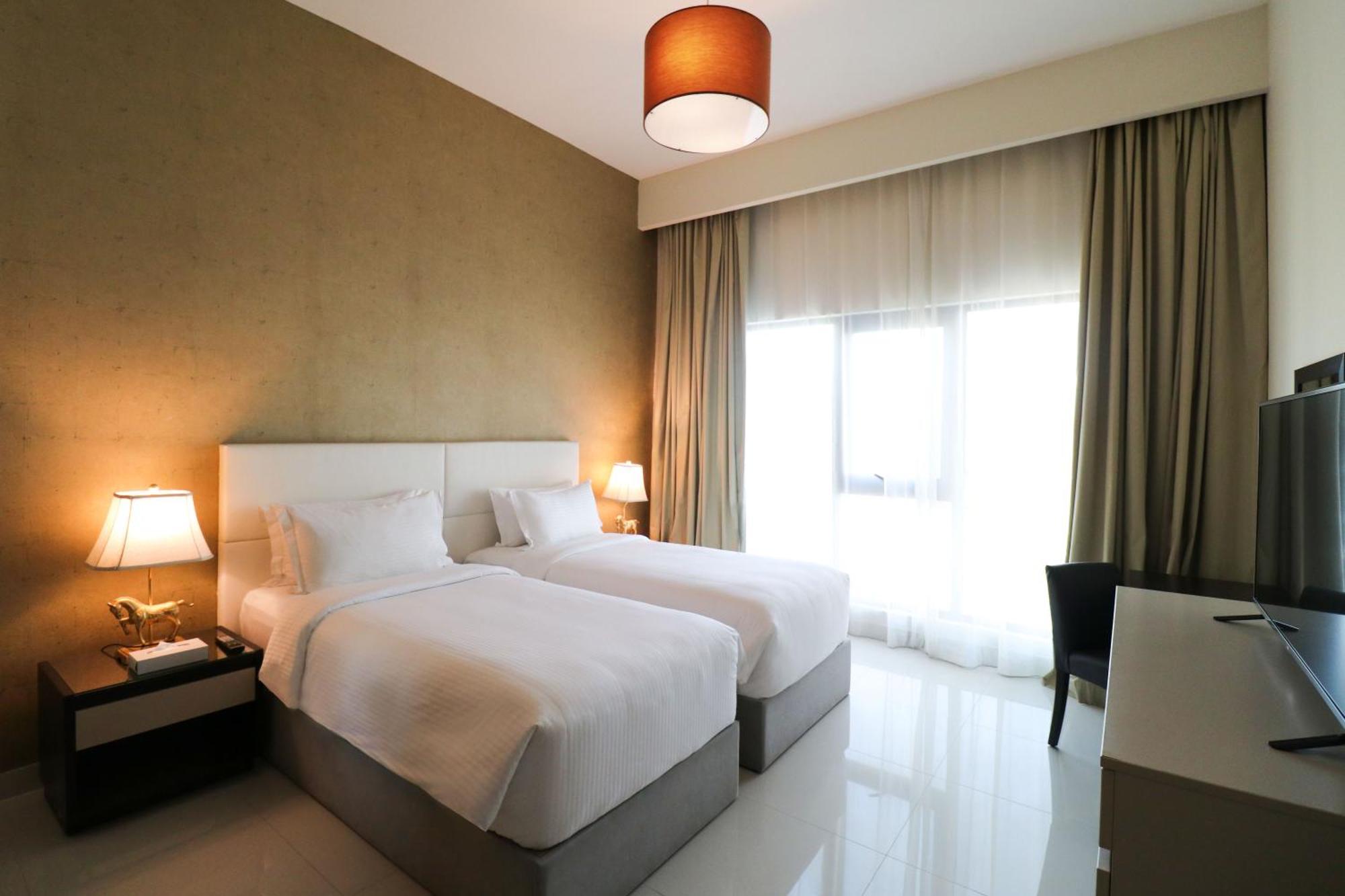 Lagoona Beach Luxury Resort And Spa Manama Exterior photo The photo shows a hotel room featuring two single beds with white bedding. The walls have a neutral tone, and there's a large window covered by light, sheer curtains allowing natural light to enter. On either side of the beds, there are bedside table